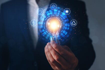 Egy férfi kezében egy világító izzó, amely körül energiahordozók ikonjaival ábrázolt digitális grafika látható.