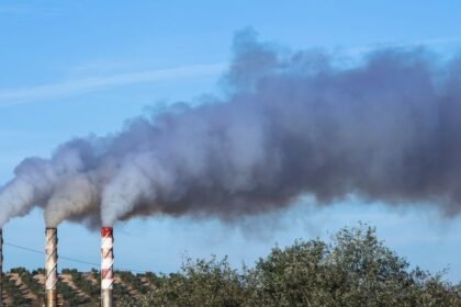 Füstölő kémények a tiszta égbolt alatt, levegőszennyezés jelei.