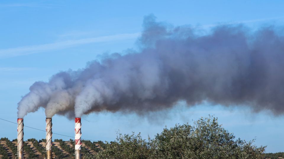 Füstölő kémények a tiszta égbolt alatt, levegőszennyezés jelei.