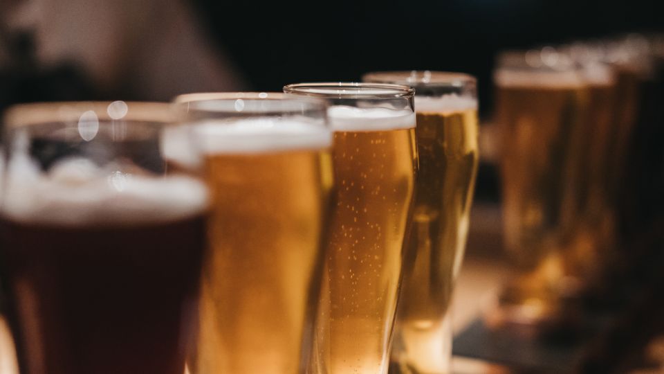 Különböző sörök sorakoznak egy asztalon, aranysárga és barna árnyalatokban.