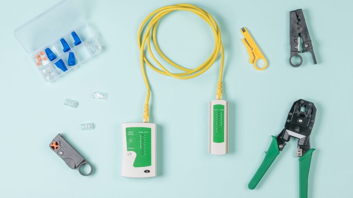 Egy UTP kábelvizsgáló és szerszámok, mint például kábelvágó és csatlakozók, egy világoskék háttéren.