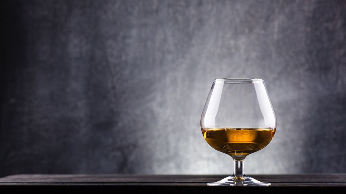 Egy elegáns pohár diópálinka áll egy sötét háttér előtt, kiemelve a folyadék aranyszínét.