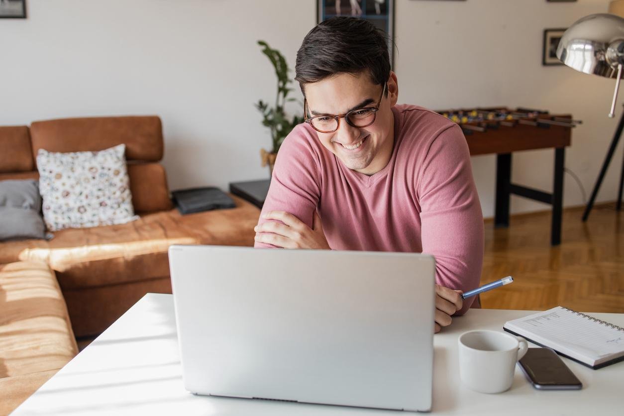 Felnőtt tanuló otthoni környezetben laptop előtt ül, online kurzust néz, koncentrálva.